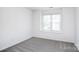 A bright bedroom with gray carpet, a large window, and white walls at 6631 Vlosi Dr, Charlotte, NC 28226