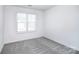 A bright bedroom with gray carpet, a large window, and white walls at 6631 Vlosi Dr, Charlotte, NC 28226