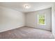 Well-lit bedroom featuring neutral walls, carpet, and a window overlooking the backyard at 7113 Amberly Hills Rd, Charlotte, NC 28215