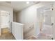 Upstairs hallway with neutral colored carpeted floors and white walls leading to rooms and bathroom at 7113 Amberly Hills Rd, Charlotte, NC 28215