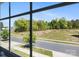 A view through the window showing a green grassy area with mature trees and a road at 7113 Amberly Hills Rd, Charlotte, NC 28215