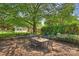 Inviting brick patio with an outdoor dining set, surrounded by beautiful landscaping and mature trees at 751 Lansdowne Rd, Charlotte, NC 28270
