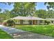 Charming brick home featuring a lush green lawn, mature trees, and a welcoming walkway leading to the front door at 751 Lansdowne Rd, Charlotte, NC 28270