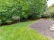 This backyard has a well-maintained lawn and mulch beds, bordered by mature trees at 8921 Magnolia Heights Ct, Charlotte, NC 28270