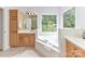 Bright bathroom featuring a soaking tub with a window view, a vanity with cabinetry, and tile flooring at 8921 Magnolia Heights Ct, Charlotte, NC 28270