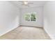 A bright bedroom with neutral carpet, ceiling fan, and a window with green outdoor views at 8921 Magnolia Heights Ct, Charlotte, NC 28270