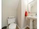Small powder room with toilet and pedestal sink with red towel and white walls at 984 Park Slope Dr, Charlotte, NC 28209