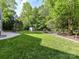 Backyard featuring a large green lawn with mature trees, shed, and flowerbed at 104 Aurora Ln, Huntersville, NC 28078