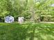 Large backyard featuring green lawn, storage shed, climbing wall, and mature trees at 104 Aurora Ln, Huntersville, NC 28078