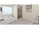 Bright bathroom featuring a soaking tub next to a frameless glass shower and a decorative painting at 105 Runningdeer Dr, Mooresville, NC 28117