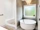 Modern bathroom showcasing a freestanding tub under a window and a glass-enclosed shower with a bench at 1123 Fern Hill Rd, Mooresville, NC 28117