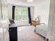 Minimalist bedroom with neutral walls, dark curtains, and a patterned bedspread, showcasing natural light at 1123 Fern Hill Rd, Mooresville, NC 28117