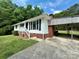 Charming single-story home with white siding, brick accents, and a covered carport, surrounded by lush greenery at 12719 Cottonville Rd, Norwood, NC 28128