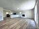 Open-concept living room with modern flooring, white brick fireplace, and seamless flow to the kitchen at 12719 Cottonville Rd, Norwood, NC 28128