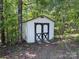 Outdoor shed in a wooded yard features a double door entry at 12719 Cottonville Rd, Norwood, NC 28128