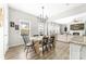 Dining area has a modern light fixture, a rustic table, and view into the living room with shiplap fireplace at 132 Moores Branch Rd, Mount Holly, NC 28120