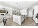 Modern kitchen features white cabinets, subway tile backsplash, an island with bar seating, and view into living room at 132 Moores Branch Rd, Mount Holly, NC 28120