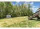 Green backyard with a shed, play set, bordered by mature trees, and stairs leading to the deck at 1336 26Th Ne Ave, Hickory, NC 28601