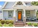 Inviting home exterior with stone pillar bases, an orange door, and a cozy seating area on the porch at 1421 Lyon Ct, Charlotte, NC 28205
