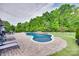 Backyard kidney-shaped pool with brick trim, lawn chairs and tree surround at 1446 Cilantro Ct, Tega Cay, SC 29708