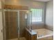 Bathroom featuring a shower and a tub, with tile surround and a window at 15326 Carrington Ridge Dr, Huntersville, NC 28078