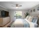 A comfortable main bedroom featuring a ceiling fan, dresser with TV, and a large window at 17810 Half Moon Ln # L, Cornelius, NC 28031