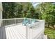 Inviting back deck with white railing and two Adirondack chairs overlooks a private, wooded backyard at 204 Myers St, Fort Mill, SC 29715
