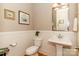 Well-lit half bathroom with pedestal sink, wainscoting, and a modern mirror at 2153 Darian Way, Waxhaw, NC 28173