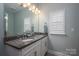 Bright bathroom featuring a double sink vanity, granite countertop and a large mirror with decorative lighting at 6029 Bountiful St, Belmont, NC 28012