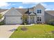 Charming two-story home with a well-manicured lawn, attached garage, and covered front porch at 6159 Holland St, Fort Mill, SC 29707