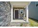 Covered front porch with stone accents, white columns, and a dark wood front door with sidelight window at 637 Scotch Meadows Loop, Monroe, NC 28110