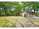 View of the backyard showcasing the brick home, detached garage, and trees at 7224 Kuck Rd, Mint Hill, NC 28227
