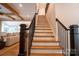 Staircase with stained wood treads and white risers and black metal railings with an open-concept living space at 724 Ideal Way, Charlotte, NC 28203