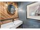 Modern powder room featuring wood accent wall, round mirror, and sleek white vessel sink at 742 Lansdowne Rd, Charlotte, NC 28270
