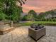 Relax outdoors on the stone patio with an outdoor fireplace and custom seating area overlooking the large backyard at 7809 Greenfield Dr, Charlotte, NC 28270