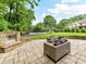 Enjoy outdoor living on the stone patio with fireplace and custom seating area with views of the spacious backyard at 7809 Greenfield Dr, Charlotte, NC 28270