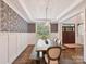 Elegant dining room with decorative wallpaper, wainscoting, modern chandelier, and hardwood floors with view to front door at 7809 Greenfield Dr, Charlotte, NC 28270