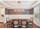 Elegant dining room with decorative wallpaper, wainscoting, modern chandelier, and hardwood floors at 7809 Greenfield Dr, Charlotte, NC 28270