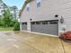 Three-car garage with contemporary doors, exterior lighting, a paved driveway, and mature landscaping at 7809 Greenfield Dr, Charlotte, NC 28270