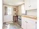 Small kitchenette area with white cabinets, a small refrigerator, and a door to the outside at 8801 Chinaberry Ln, Concord, NC 28027