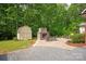 Stone patio area with outdoor fireplace and storage shed, surrounded by lush greenery at 9941 Heritage Oak Ln, Waxhaw, NC 28173