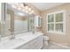Bright bathroom with double vanity, white cabinetry, and large framed mirror with natural light from shuttered window at 1000 Rudd Rd, Gastonia, NC 28054