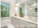 Bright bathroom with double vanity, white cabinets, and a window at 10528 Audubon Ridge Dr, Cornelius, NC 28031