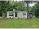 Charming single-story home with white brick, dark door and window boxes nestled among mature trees at 13131 601 S Hwy, Midland, NC 28107