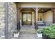 Inviting front porch with stone accents and decorative double doors with a cozy seating area at 15909 Heath Aster Way, Davidson, NC 28036