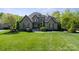Charming stone facade home featuring mature trees, lush landscaping, and a well-manicured lawn at 15909 Heath Aster Way, Davidson, NC 28036