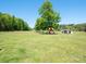 Large, level backyard with established trees includes a playset and sheds offering space for outdoor fun at 2008 Faulkner Rd, Clover, SC 29710
