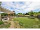 Lush backyard with a covered patio, play equipment, a garden and a well-maintained lawn at 235 Whispering Hills Dr, Locust, NC 28097