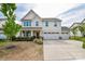Two-story home features a three-car garage, covered porch with rocking chairs, and well-maintained landscaping at 235 Whispering Hills Dr, Locust, NC 28097