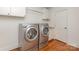 Laundry room featuring wood floors, white cabinets and modern washer and dryer at 4467 Woodlark Ln, Charlotte, NC 28211
